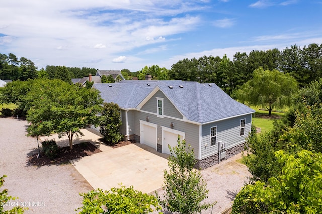 view of front of property featuring a garage, roof with shingles, and driveway