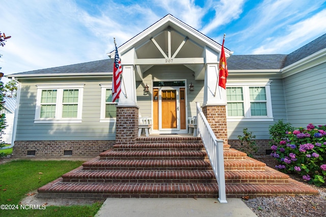 entrance to property with crawl space, brick siding, and roof with shingles