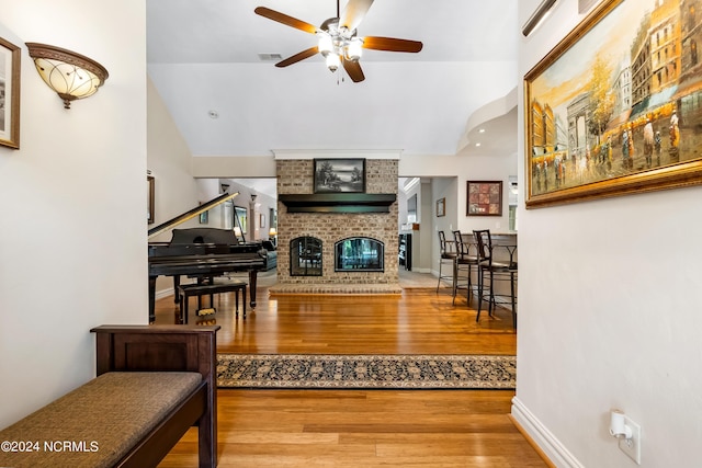 living room featuring a fireplace, visible vents, a ceiling fan, wood finished floors, and baseboards