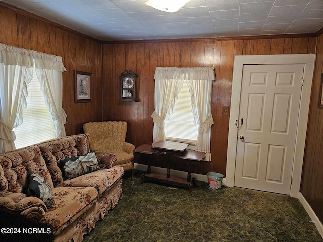 carpeted living room featuring wooden walls and ornamental molding