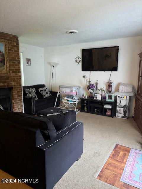 living room featuring a textured ceiling, carpet floors, and a brick fireplace