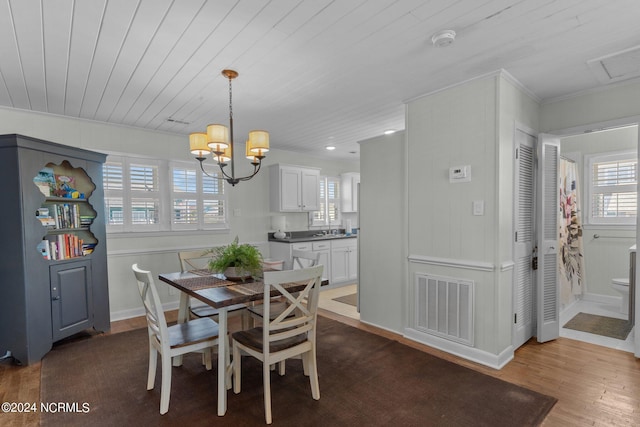 dining space featuring wooden ceiling, sink, crown molding, hardwood / wood-style flooring, and a chandelier