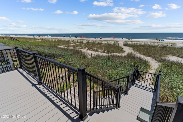 wooden deck with a water view and a beach view