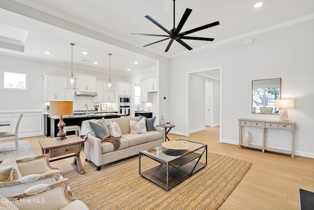 living room with sink, crown molding, ceiling fan, and light wood-type flooring