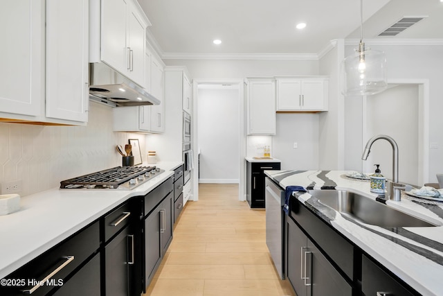 kitchen with hanging light fixtures, crown molding, white cabinets, and stainless steel appliances