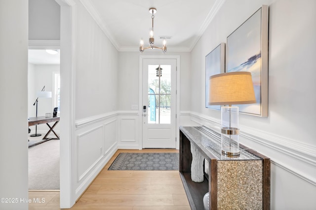 entrance foyer with a notable chandelier, light hardwood / wood-style flooring, and ornamental molding