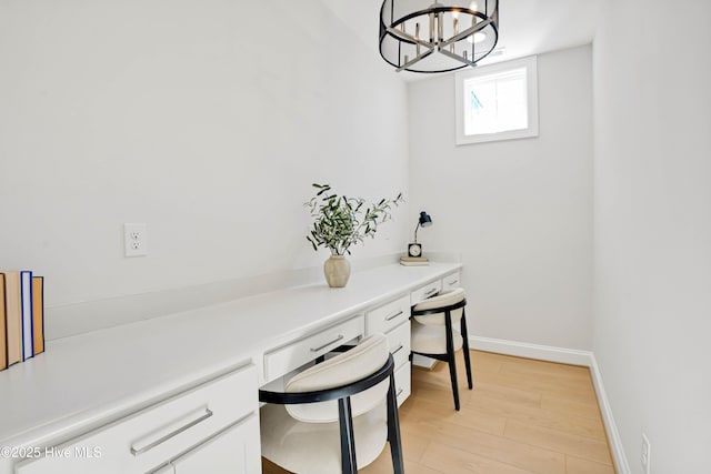 office space featuring a notable chandelier, built in desk, and light wood-type flooring