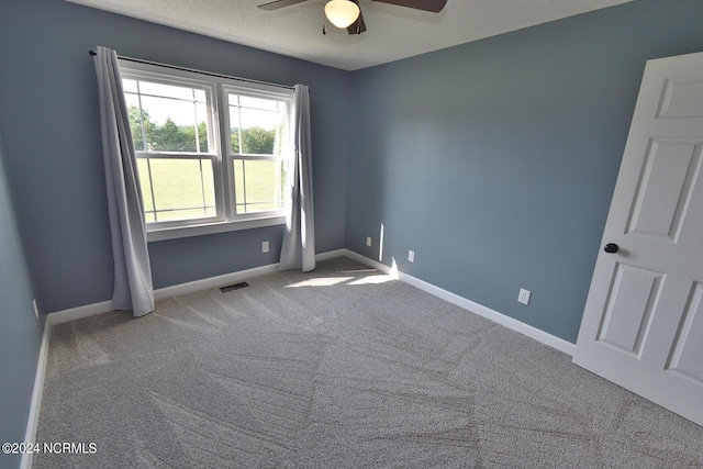 carpeted empty room featuring ceiling fan and a textured ceiling