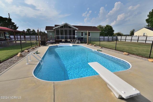 view of swimming pool with a sunroom, a patio, a diving board, and a lawn