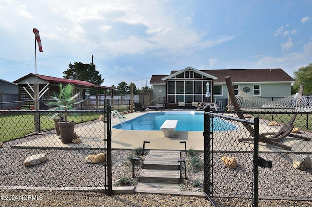 view of swimming pool featuring a sunroom, a diving board, and a patio