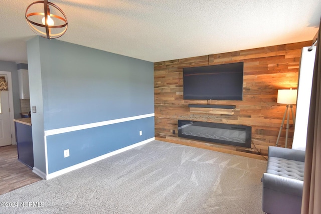 unfurnished living room featuring carpet, a textured ceiling, and wooden walls