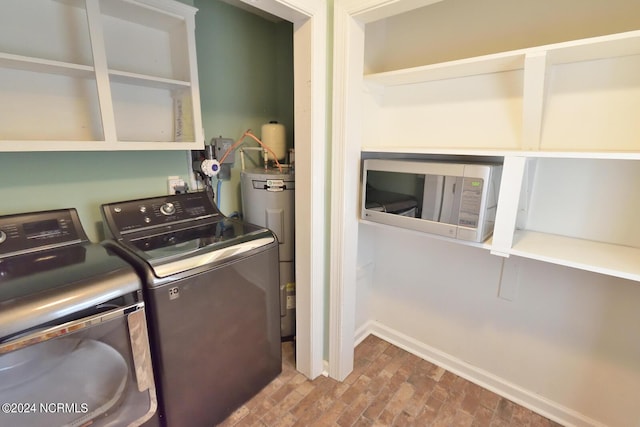 washroom with washing machine and clothes dryer and water heater