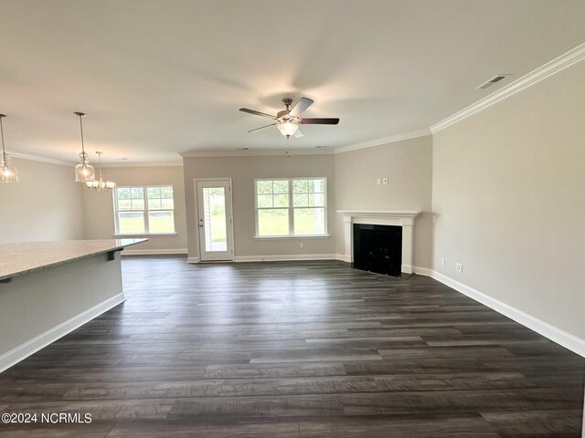 unfurnished living room with ceiling fan with notable chandelier, dark hardwood / wood-style floors, and ornamental molding