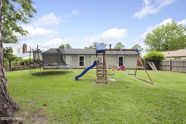 rear view of property featuring a playground, a trampoline, and a yard