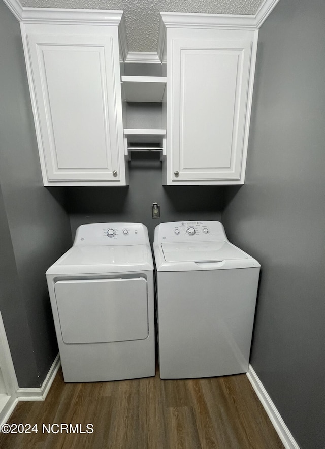 laundry area with cabinets, dark wood-type flooring, washer and dryer, ornamental molding, and a textured ceiling