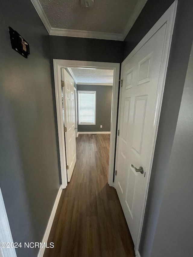 hall featuring a textured ceiling, crown molding, and dark wood-type flooring