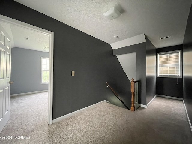 stairway featuring carpet flooring and a textured ceiling