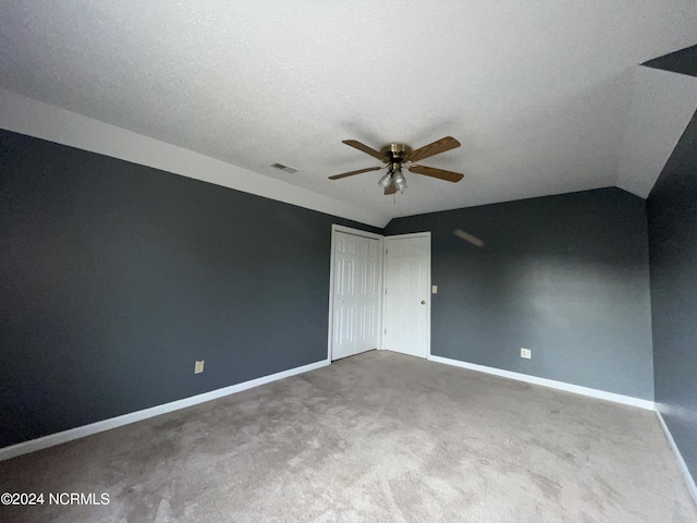 empty room featuring carpet, a textured ceiling, vaulted ceiling, and ceiling fan