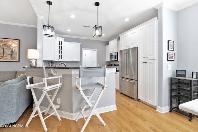 kitchen with kitchen peninsula, white cabinets, hanging light fixtures, and appliances with stainless steel finishes