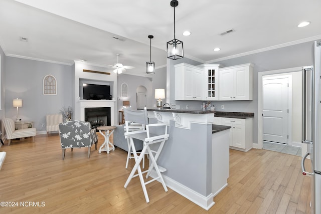 kitchen with white cabinets, ceiling fan, light hardwood / wood-style floors, and radiator