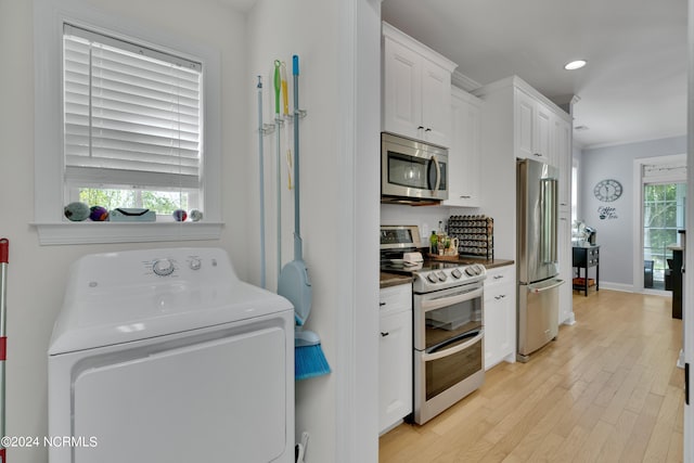 kitchen featuring washer / clothes dryer, a wealth of natural light, white cabinets, and appliances with stainless steel finishes