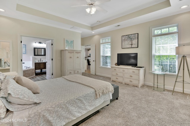 carpeted bedroom featuring ceiling fan, a raised ceiling, and connected bathroom