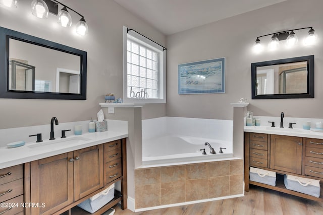 bathroom with vanity, a relaxing tiled tub, and wood-type flooring