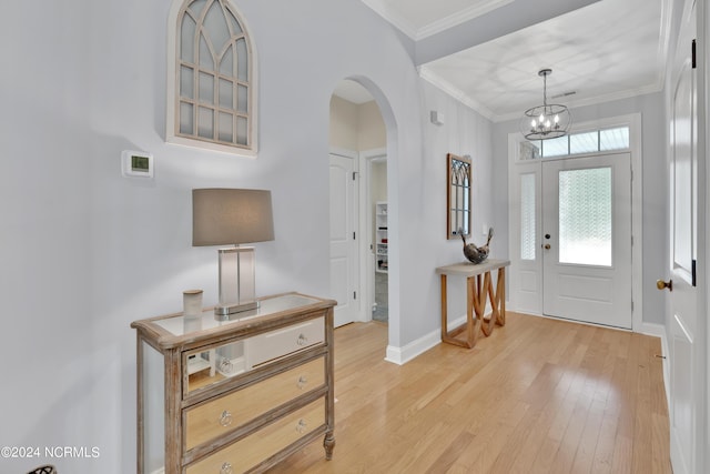 foyer entrance with crown molding, light hardwood / wood-style flooring, and an inviting chandelier