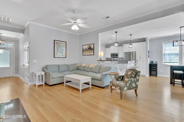 living room featuring ceiling fan with notable chandelier, light hardwood / wood-style floors, and crown molding