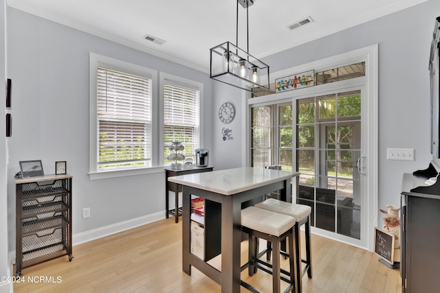 dining space featuring light hardwood / wood-style floors, crown molding, and a notable chandelier