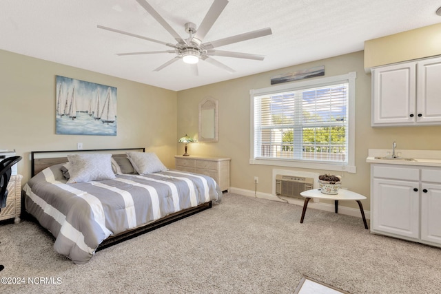 bedroom with ceiling fan, light carpet, sink, and a wall unit AC