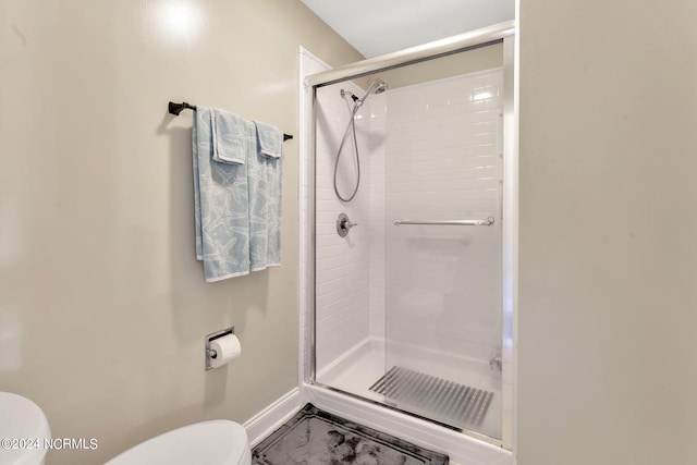 bathroom with a shower with shower door and toilet