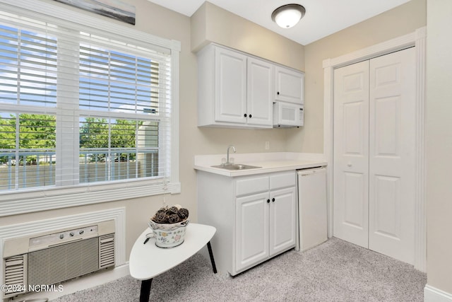 interior space featuring sink, white cabinets, light colored carpet, white appliances, and a wall mounted air conditioner