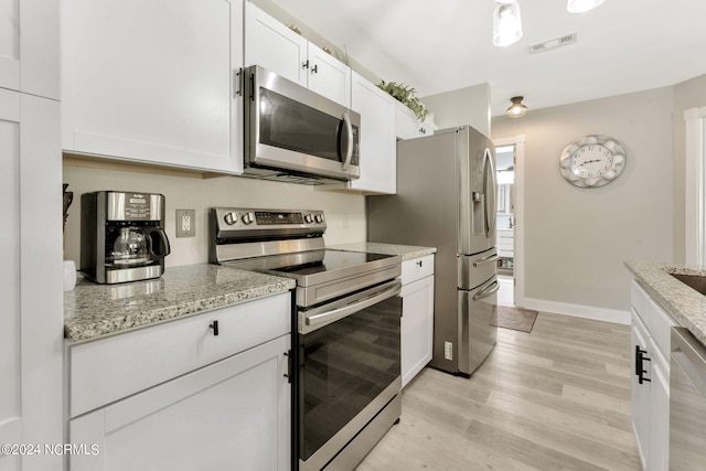 kitchen with appliances with stainless steel finishes, light wood-type flooring, white cabinetry, and light stone countertops