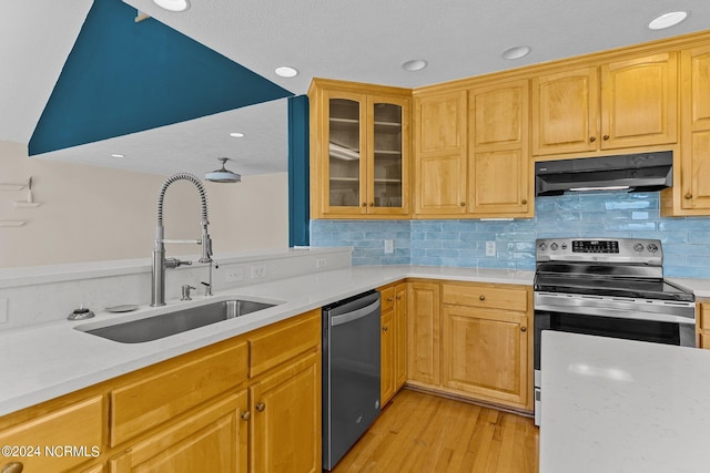 kitchen with tasteful backsplash, sink, stainless steel appliances, and light hardwood / wood-style floors