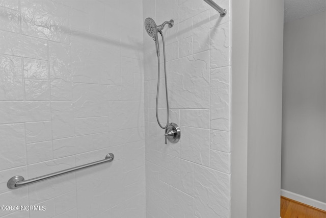 bathroom featuring a tile shower and wood-type flooring