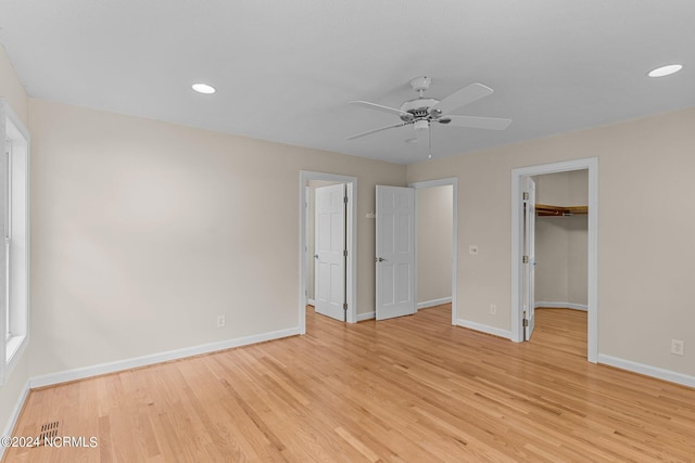 unfurnished bedroom featuring ceiling fan, light wood-type flooring, a spacious closet, and a closet