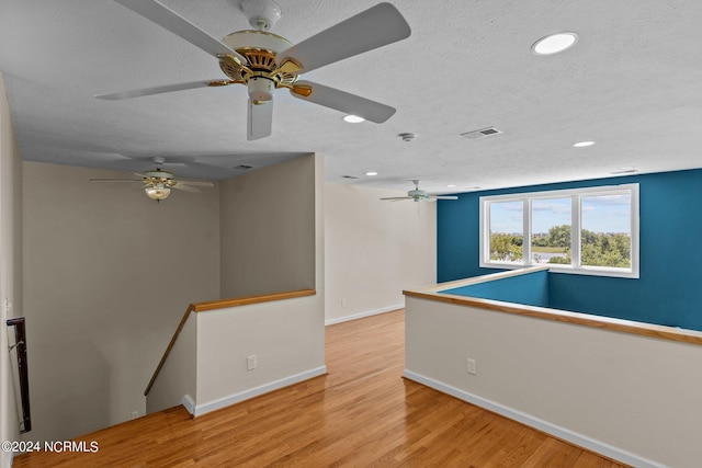 spare room featuring ceiling fan, a textured ceiling, and light wood-type flooring