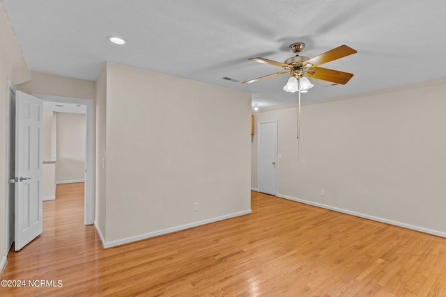 empty room with ceiling fan, light hardwood / wood-style floors, and a textured ceiling