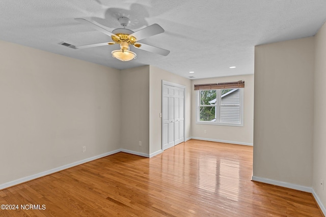 unfurnished room featuring a textured ceiling, light hardwood / wood-style flooring, and ceiling fan