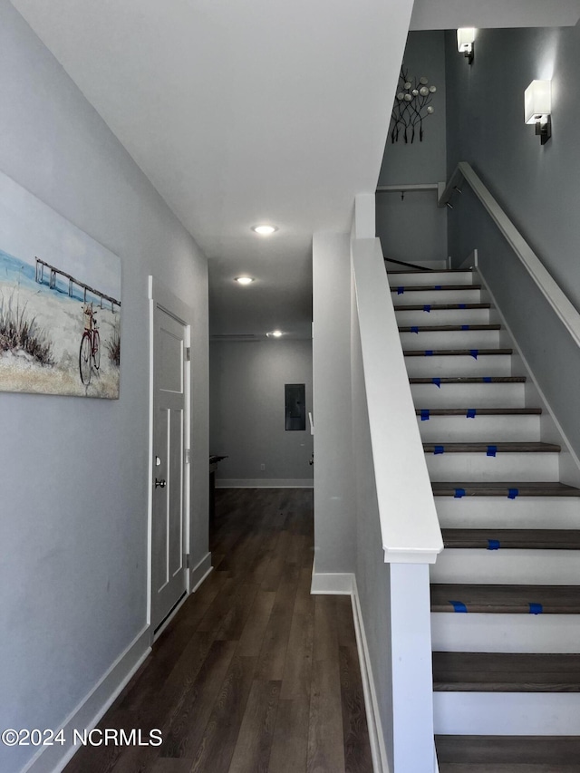 staircase featuring electric panel and hardwood / wood-style floors