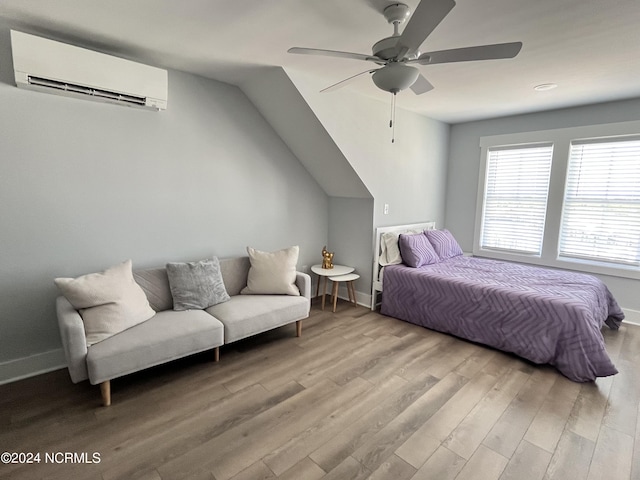 bedroom featuring ceiling fan, light wood-type flooring, and an AC wall unit