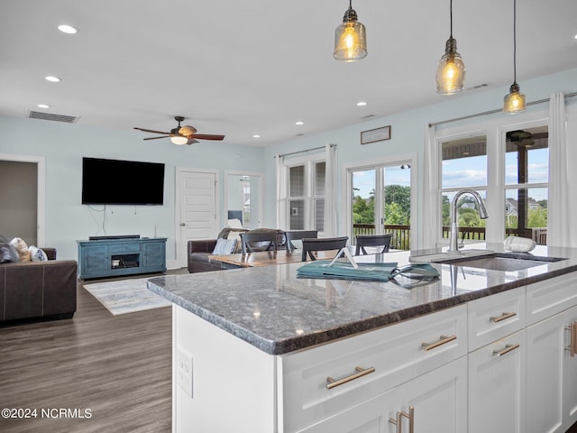 kitchen featuring dark stone countertops, sink, white cabinets, and hanging light fixtures