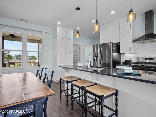 kitchen with dark hardwood / wood-style floors, white cabinetry, stainless steel appliances, and wall chimney range hood