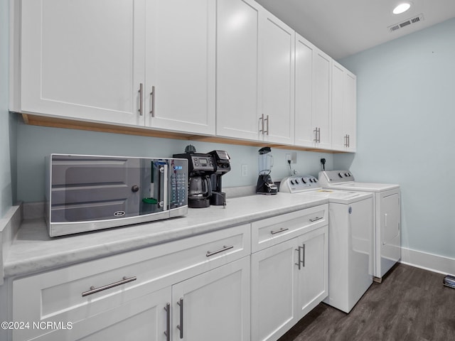 laundry area featuring washing machine and dryer, cabinets, and dark hardwood / wood-style floors