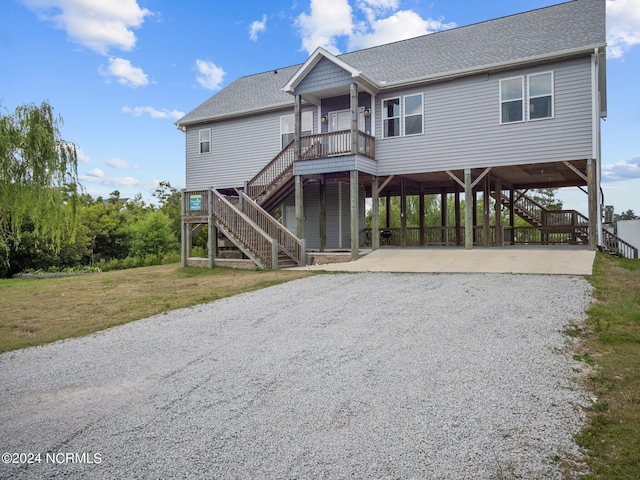 beach home with a front lawn, covered porch, and a carport