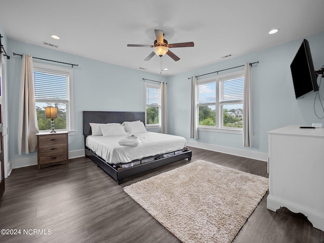 bedroom featuring ceiling fan, dark wood-type flooring, and multiple windows