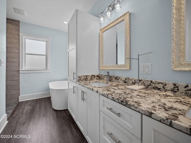 bathroom with wood-type flooring, vanity, and a tub to relax in