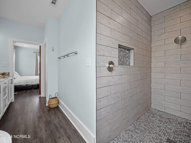 bathroom with tiled shower and hardwood / wood-style floors