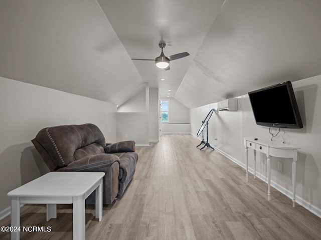 living room with a wall mounted air conditioner, light hardwood / wood-style flooring, vaulted ceiling, and ceiling fan